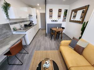 a living room with a couch and a kitchen at Le Refuge du Bord de Mer 2 pers- Studio avec parking à 500m de la mer in Houlgate