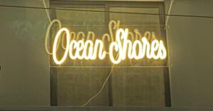 Un'insegna al neon che dice orologi oceanici su una finestra di Ocean Shores a Chennai