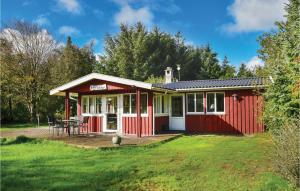 uma casa vermelha com um deque num quintal em Valndden em Søndervig