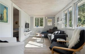 uma sala de estar com um sofá, cadeiras e janelas em Valndden em Søndervig