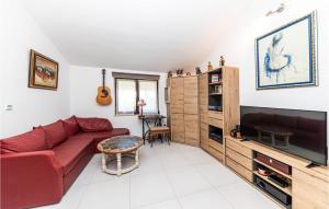 a living room with a red couch and a flat screen tv at Cozy Apartment In Kastel Novi in Kastel Novi