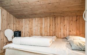 a bed in a room with a wooden wall at Nice Home In Hjrring With 3 Bedrooms And Wifi in Lønstrup