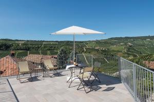 a patio with a table and chairs and an umbrella at Residence delle Rose in Barolo