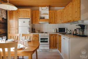 une cuisine avec des armoires en bois et un four blanc dans l'établissement Holiday in Lapland - Levin Sudenpesä, à Levi