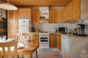 a kitchen with wooden cabinets and a white stove top oven at Holiday in Lapland - Levin Sudenpesä in Sirkka