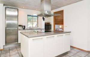 cocina con armarios blancos y nevera de acero inoxidable en Amazing Home In Blvand With 5 Bedrooms, Sauna And Indoor Swimming Pool en Blåvand
