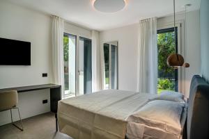 Schlafzimmer mit einem Bett, einem TV und Fenstern in der Unterkunft Appartamento Midum Garden Sud in Trient