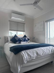 a white bedroom with a large bed with blue pillows at 14 on Braemar in Durban