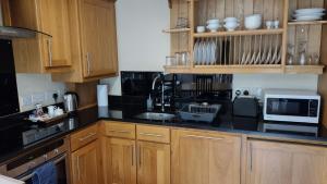 cocina con armarios de madera y encimera negra en Shieling Cottage at Lovelady Shield, en Alston