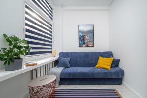 een blauwe bank in een kamer met een raam bij Studios K1A in Vilnius