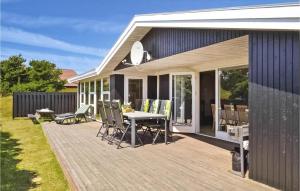 a deck with a table and chairs on a house at Pet Friendly Home In Hvide Sande With Kitchen in Havrvig