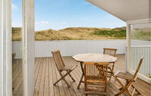 eine Veranda mit einem Holztisch und Stühlen darauf in der Unterkunft Nice Home In Hvide Sande With 3 Bedrooms, Sauna And Wifi in Hvide Sande