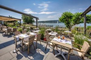 ein Restaurant mit Tischen und Stühlen und Blick auf das Wasser in der Unterkunft Strandhotel Löchnerhaus in Reichenau