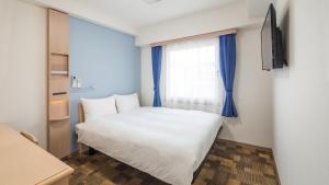Un pequeño dormitorio con una cama blanca y una ventana en Toyoko Inn Nagoya-eki Sakuradori-guchi Shinkan en Nagoya