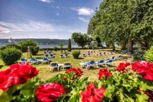 a group of chairs and red flowers in a park at Strandhotel Löchnerhaus in Reichenau