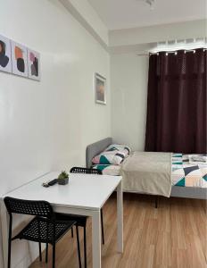 Biñan的住宿－Neat Unit in Holland Park Southwoods，小房间设有一张床、一张桌子和椅子