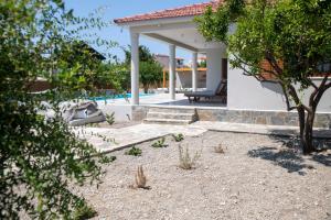a house with a patio and a tree in the yard at Avli Guest House in Tympáki