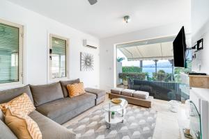 ein Wohnzimmer mit einem Sofa und einem TV in der Unterkunft Beach Front Villa Mer Blu by Ezoria Villas in Coral Bay