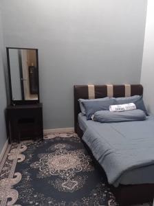 um quarto com uma cama, um espelho e um tapete em Aisyah Homestay Kuantan - Jaya Gading em Kampong Seri Permatang Gading