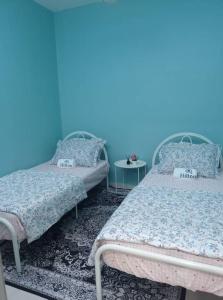Duas camas num quarto com uma parede azul em Aisyah Homestay Kuantan - Jaya Gading em Kampong Seri Permatang Gading