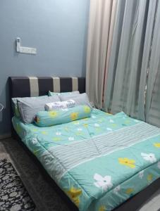 a bed with a blue comforter and pillows on it at Aisyah Homestay Kuantan - Jaya Gading in Kampong Seri Permatang Gading