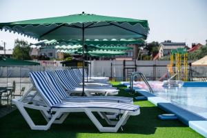 - une rangée de chaises longues et un parasol à côté de la piscine dans l'établissement Weekend Family Hotel, à Karolino-Buhaz