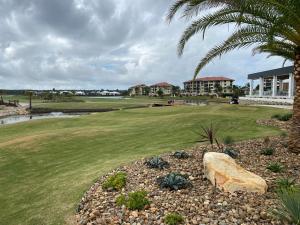 a golf course with a palm tree and a green at Pelican Waters Resort One Bedroom Apartment in Pelican Waters