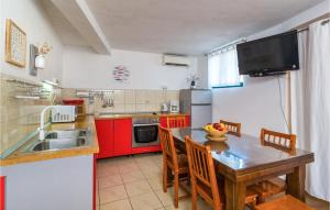 a kitchen with red cabinets and a table with chairs at 3 Bedroom Beautiful Apartment In Mirca in Mirce