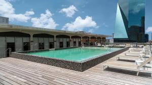 uma piscina no topo de um edifício com um deque de madeira em Bold CozySuites with pool, gym, roof #8 em Dallas