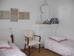 ein Schlafzimmer mit einem Bett, einem Stuhl und einem Spiegel in der Unterkunft Maison de famille sur l'île de Groix in Groix