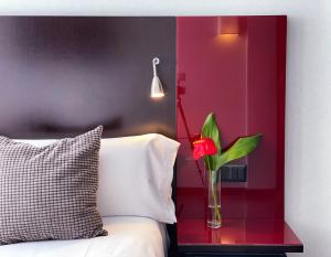 a vase with a red flower on a table next to a bed at SM Hotel Sant Antoni in Barcelona