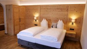 Schlafzimmer mit einem großen weißen Bett und Holzwänden in der Unterkunft Bucherwirt Appartements in Buch bei Jenbach