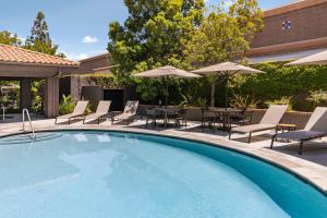 a swimming pool with chairs and tables and umbrellas at Courtyard Ventura Simi Valley in Simi Valley