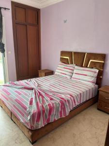 1 dormitorio con 1 cama grande con sábanas y almohadas a rayas en Appartement au bord de l'eau, en Mohammedia 21 fotos más