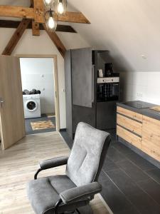 a living room with a chair and a kitchen at Apartment am Stettiner Haff in Mönkebude