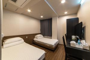 a room with two beds and a desk with a phone at Soosong Guesthouse in Seoul