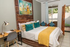 a bedroom with a bed and a desk and a window at Biweda Nguni Lodge in Mkuze