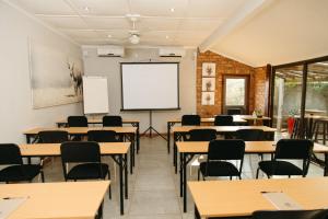 an empty classroom with tables and chairs and a whiteboard at Biweda Nguni Lodge in Mkuze +99 photos