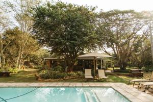 een zwembad in een tuin met een tafel en stoelen bij Biweda Nguni Lodge in Mkuze