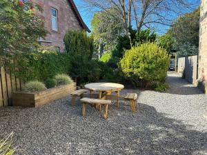 a picnic table and two benches in a garden at Period House / Entire Upstairs Flat in Inverness