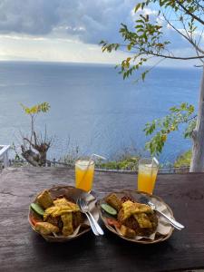 two plates of food and two glasses of orange juice at Eco Tourist Dream Stay Tree House in Nusa Penida