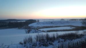 een veld bedekt met sneeuw met de zonsondergang op de achtergrond bij Wyskok 1 - dom z widokiem in Srokowo