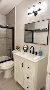 een badkamer met een wastafel, een toilet en een spiegel bij King Suite near SpaceX, SoFI, LAX and Sout Bay Beaches in Gardena