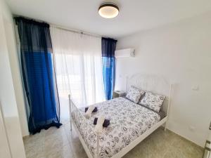 Schlafzimmer mit einem weißen Bett und blauen Vorhängen in der Unterkunft Beach Vibes Apartment in Pyla