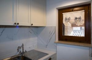 a kitchen with a sink and a window with bows at Residenza Porta Perlici Assisi Apartment in Assisi