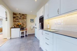 cocina con armarios blancos y pared de piedra en Superb Panoramic Sea Views Sleeps 10 Pet Friendly, en Woolacombe 20 fotos más