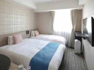 a hotel room with two beds and a window at Vessel Inn Shigamoriyamaekimae in Moriyama