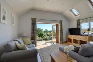 a living room with two couches and a tv at 2 bed garden cottage nestled on the edge of Exmoor in Bishops Nympton