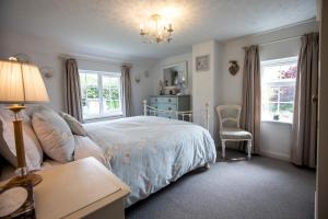 a bedroom with a bed and a chair and windows at 2 bed garden cottage nestled on the edge of Exmoor in Bishops Nympton