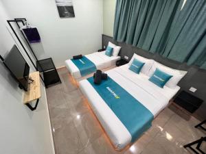 2 Betten in einem kleinen Zimmer mit einem TV in der Unterkunft BEATRIX HOTEL in Brinchang